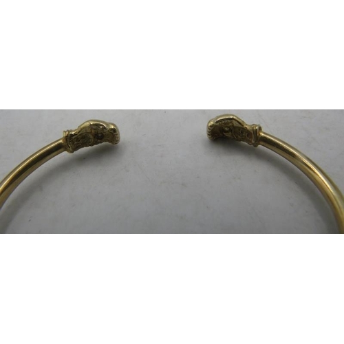 433 - A 9ct yellow gold bangle with boxing glove terminals each set with a white stone. Approx weight 5.5 ... 