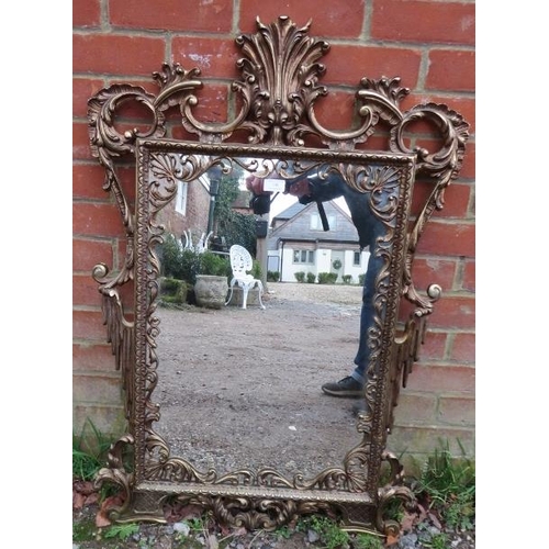 709 - A vintage gilt brass wall mirror in the George II taste, having a very ornate pierced surround model... 