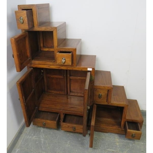 717 - A vintage Chinese elm stepped room-divider, housing an array of six double-sided drawers and three c... 