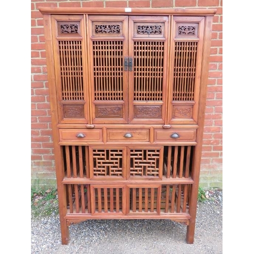 719 - A vintage Chinese elm kitchen cupboard, having carved and pierced decoration and slatted doors openi... 