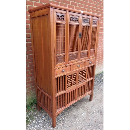 719 - A vintage Chinese elm kitchen cupboard, having carved and pierced decoration and slatted doors openi... 