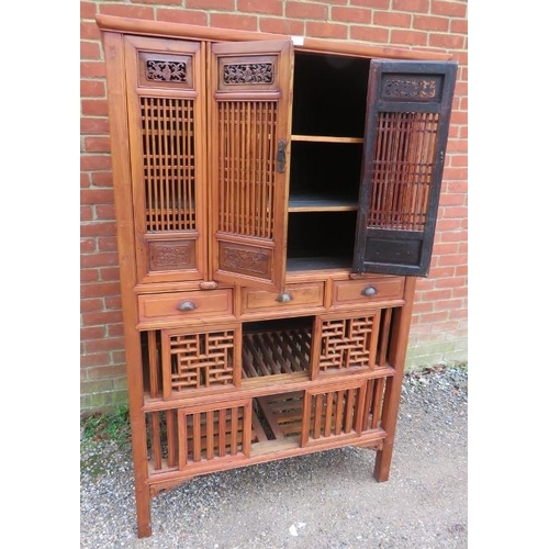 719 - A vintage Chinese elm kitchen cupboard, having carved and pierced decoration and slatted doors openi... 