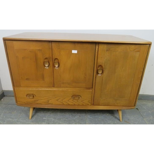 727 - A mid-century blonde elm and beech Windsor sideboard by Ercol (model 467) having cupboard doors encl... 