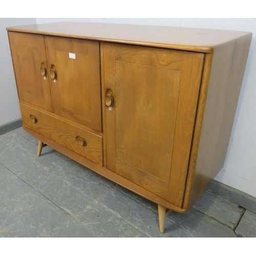 727 - A mid-century blonde elm and beech Windsor sideboard by Ercol (model 467) having cupboard doors encl... 