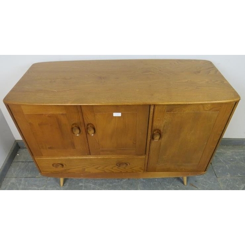 727 - A mid-century blonde elm and beech Windsor sideboard by Ercol (model 467) having cupboard doors encl... 