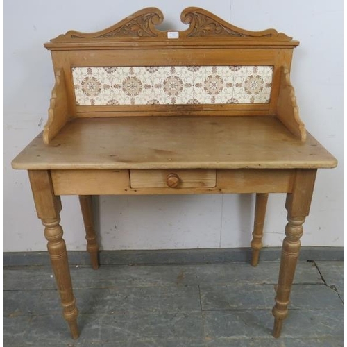 735 - An antique pine washstand, having acanthus carved and scrolled cornice, above an inset tile back, on... 