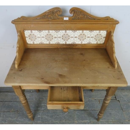 735 - An antique pine washstand, having acanthus carved and scrolled cornice, above an inset tile back, on... 