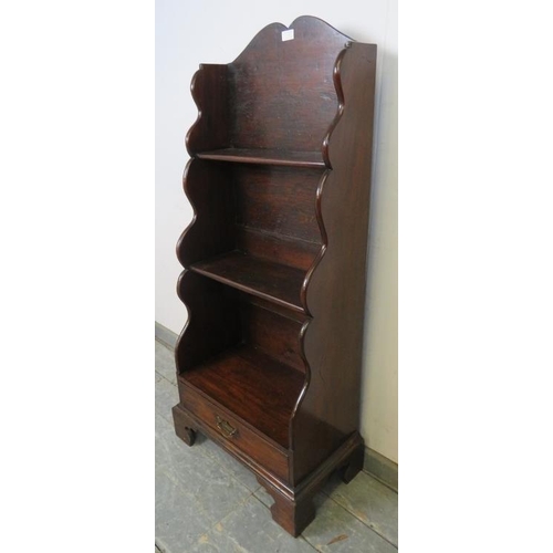 738 - A George III mahogany ‘waterfall’ narrow bookcase of three graduated open shelves, above one long dr... 