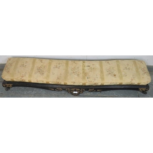 744 - A 19th century long low footstool, with loose cushion, the ebonised base with relief decoration pain... 