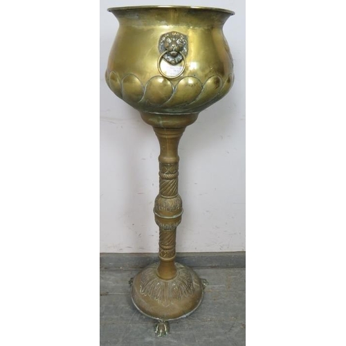 753 - An antique brass pedestal jardinière planter, having relief decoration depicting an armorial crest a... 