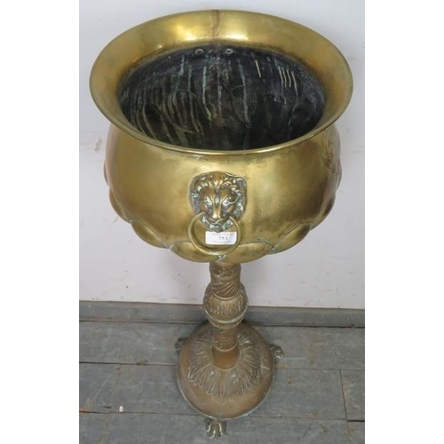 753 - An antique brass pedestal jardinière planter, having relief decoration depicting an armorial crest a... 