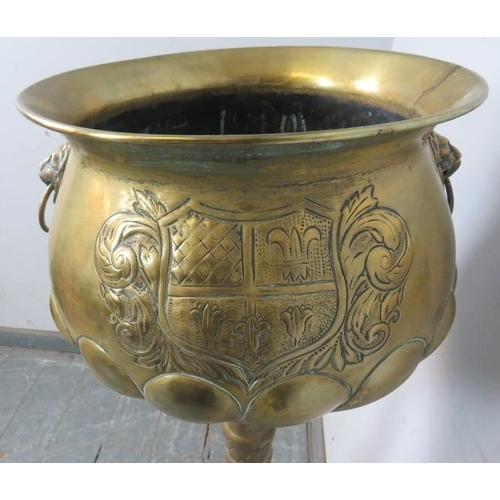 753 - An antique brass pedestal jardinière planter, having relief decoration depicting an armorial crest a... 