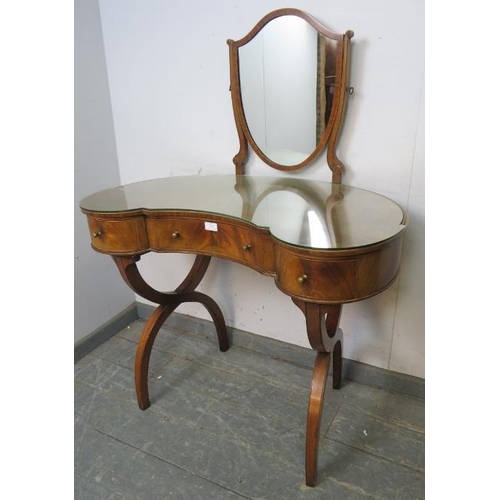 770 - A vintage mahogany kidney-shaped dressing table in the Regency style, having a shield shaped mirror ... 