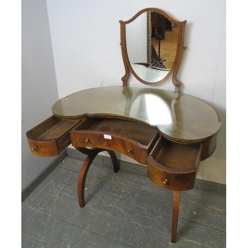 770 - A vintage mahogany kidney-shaped dressing table in the Regency style, having a shield shaped mirror ... 