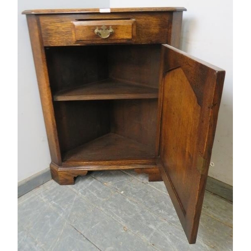 774 - A reproduction solid oak floor-standing corner cupboard in the 18th century taste, having one short ... 