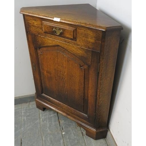 774 - A reproduction solid oak floor-standing corner cupboard in the 18th century taste, having one short ... 