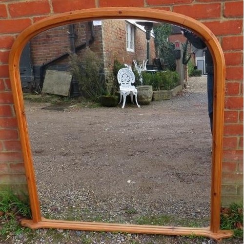 779 - A large arched over-mantle mirror, within a pine surround with a shaped plinth base. 
H121cm W127cm ... 