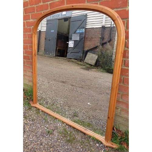 779 - A large arched over-mantle mirror, within a pine surround with a shaped plinth base. 
H121cm W127cm ... 