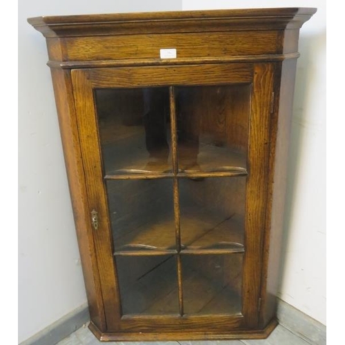 794 - A reproduction solid oak hanging corner cabinet, the gazed door opening onto two shaped shelves. 
H1... 