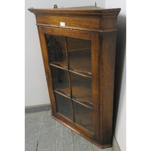 794 - A reproduction solid oak hanging corner cabinet, the gazed door opening onto two shaped shelves. 
H1... 