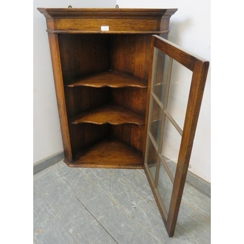 794 - A reproduction solid oak hanging corner cabinet, the gazed door opening onto two shaped shelves. 
H1... 