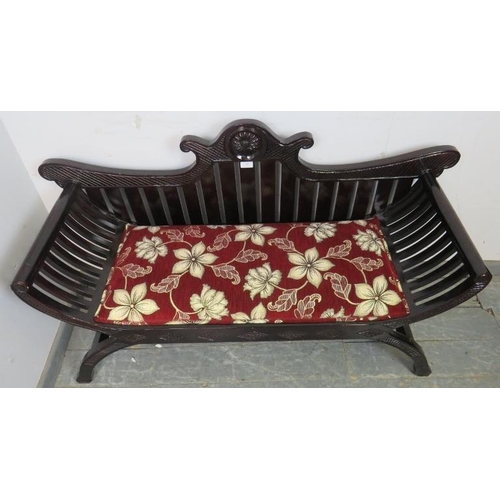 805 - An antique style ebonised hardwood love seat, with shaped cornice and slatted back, upholstered in a... 