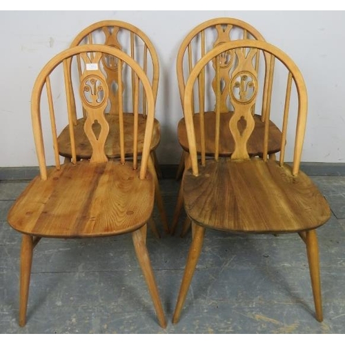 809 - A set of four mid-century elm and beech blonde fleur de lis dining chairs by Ercol, on canted suppor... 