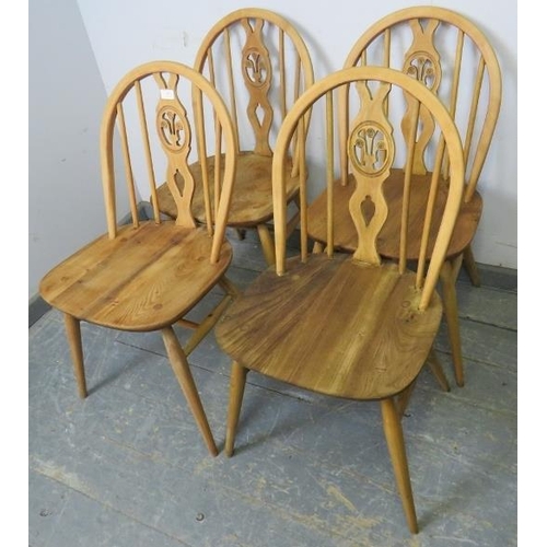 809 - A set of four mid-century elm and beech blonde fleur de lis dining chairs by Ercol, on canted suppor... 