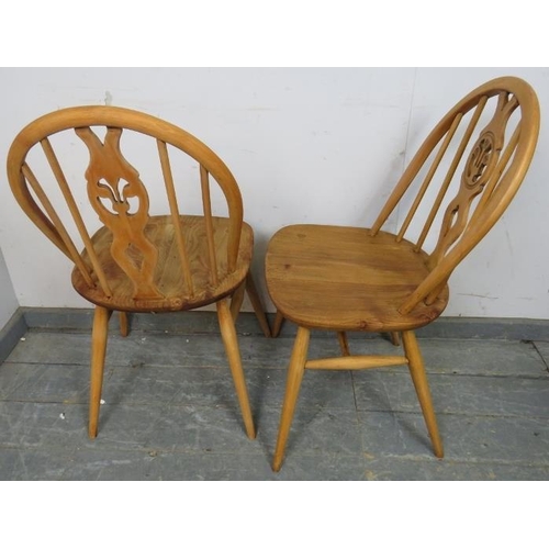 809 - A set of four mid-century elm and beech blonde fleur de lis dining chairs by Ercol, on canted suppor... 