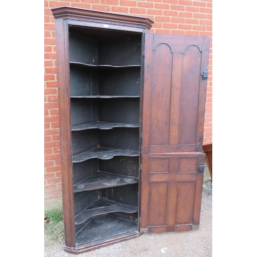 825 - An 18th century oak tall corner cupboard, the two doors with carved and fielded panels opening onto ... 