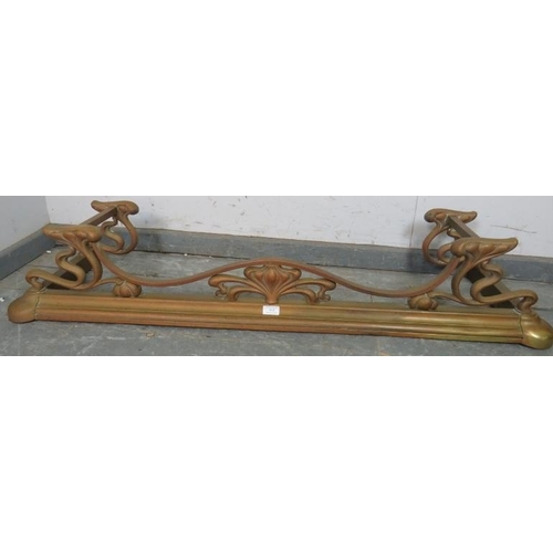 842 - An Art Nouveau brass fire fender, having an ornately shaped and pierced gallery, on a plinth base wi... 