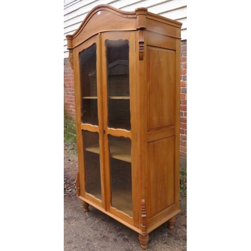 856 - An antique pine Continental glazed display cabinet, the shaped cornice above acanthus carved corbels... 