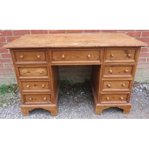 884 - A vintage pine kneehole desk, having a configuration of nine drawers with turned wooden knob handles... 