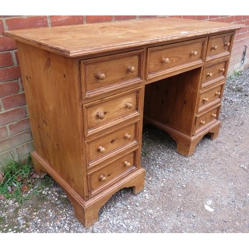 884 - A vintage pine kneehole desk, having a configuration of nine drawers with turned wooden knob handles... 