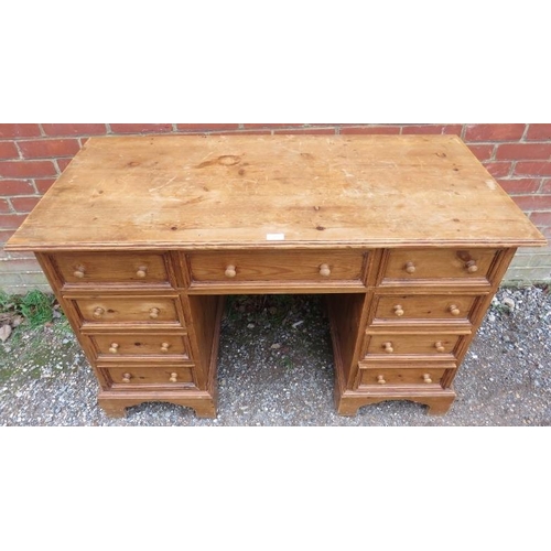 884 - A vintage pine kneehole desk, having a configuration of nine drawers with turned wooden knob handles... 