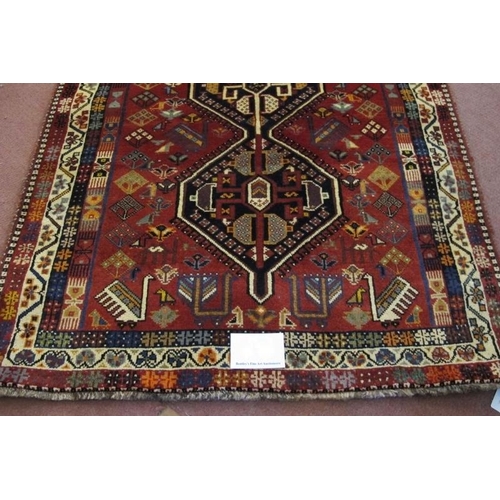 903 - A good South West Persian Qashqai rug in central motif of three interlocking panels on a soft red gr... 