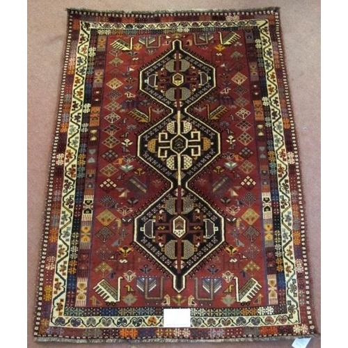 903 - A good South West Persian Qashqai rug in central motif of three interlocking panels on a soft red gr... 