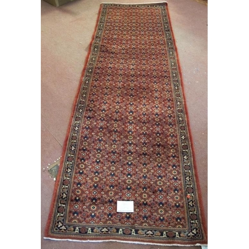 911 - A North West Persian Bidsar runner with a central repeat pattern field on a pale red ground. 300cm x... 