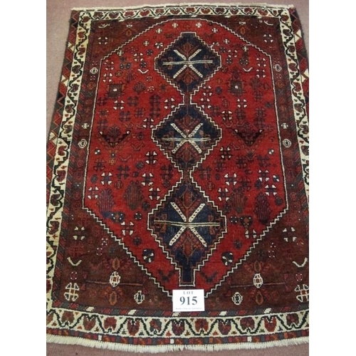 915 - A mid 20th century Persian rug, three central linked medallions on a deep red ground, in good condit... 