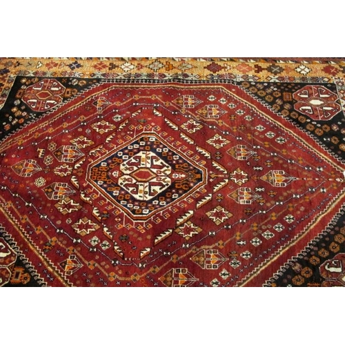 916 - A mid-late 20th century Persian rug, with a central motif on red ground with four motifs in each cor... 