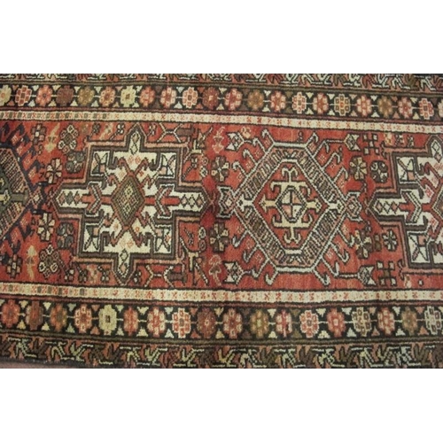 922 - A 20th century Persian runner, seven large central motifs on a red ground. Colour and condition good... 