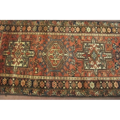 922 - A 20th century Persian runner, seven large central motifs on a red ground. Colour and condition good... 