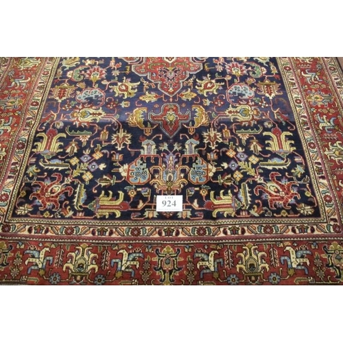 924 - A fine Persian Tabriz carpet. Central medallion, red on blue ground, deep borders and in excellent c... 