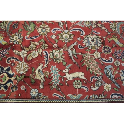 925 - An excellent Persian Tabriz carpet. A large central panel on red ground depicting animals - deer, bi... 