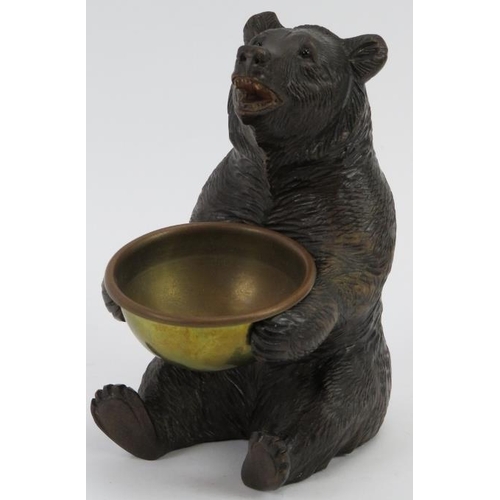 17 - A finely carved Black Forest bear holding a brass bowl. Modelled with glass eyes. Possibly to be uti... 