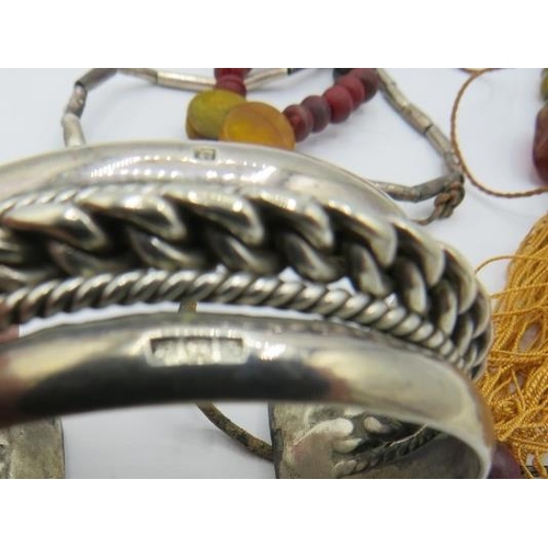 329 - A heavy Egyptian silver bangle, a bead necklace with various semi-precious stones, a silver & amber ... 