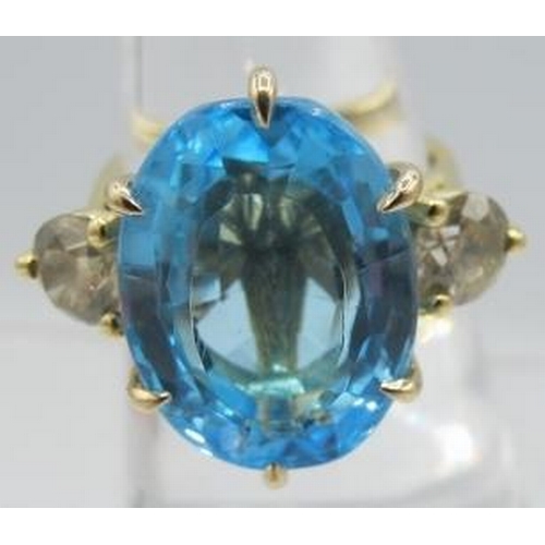 438 - A certificated 18ct yellow gold ring set with a large oval blue topaz, flanked by round brilliant di... 