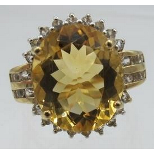 447 - A 9ct yellow gold ring set with a large oval citrine & several round brilliant cut topaz, size M. Ci... 