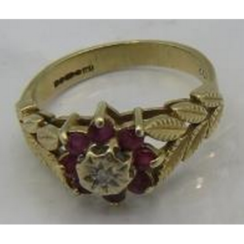 483 - A 9ct yellow gold flower ring set with small centre diamond & eight rubies. The shoulders of gold ca... 