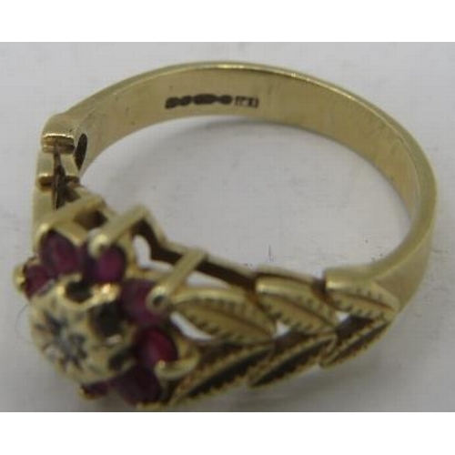 483 - A 9ct yellow gold flower ring set with small centre diamond & eight rubies. The shoulders of gold ca... 